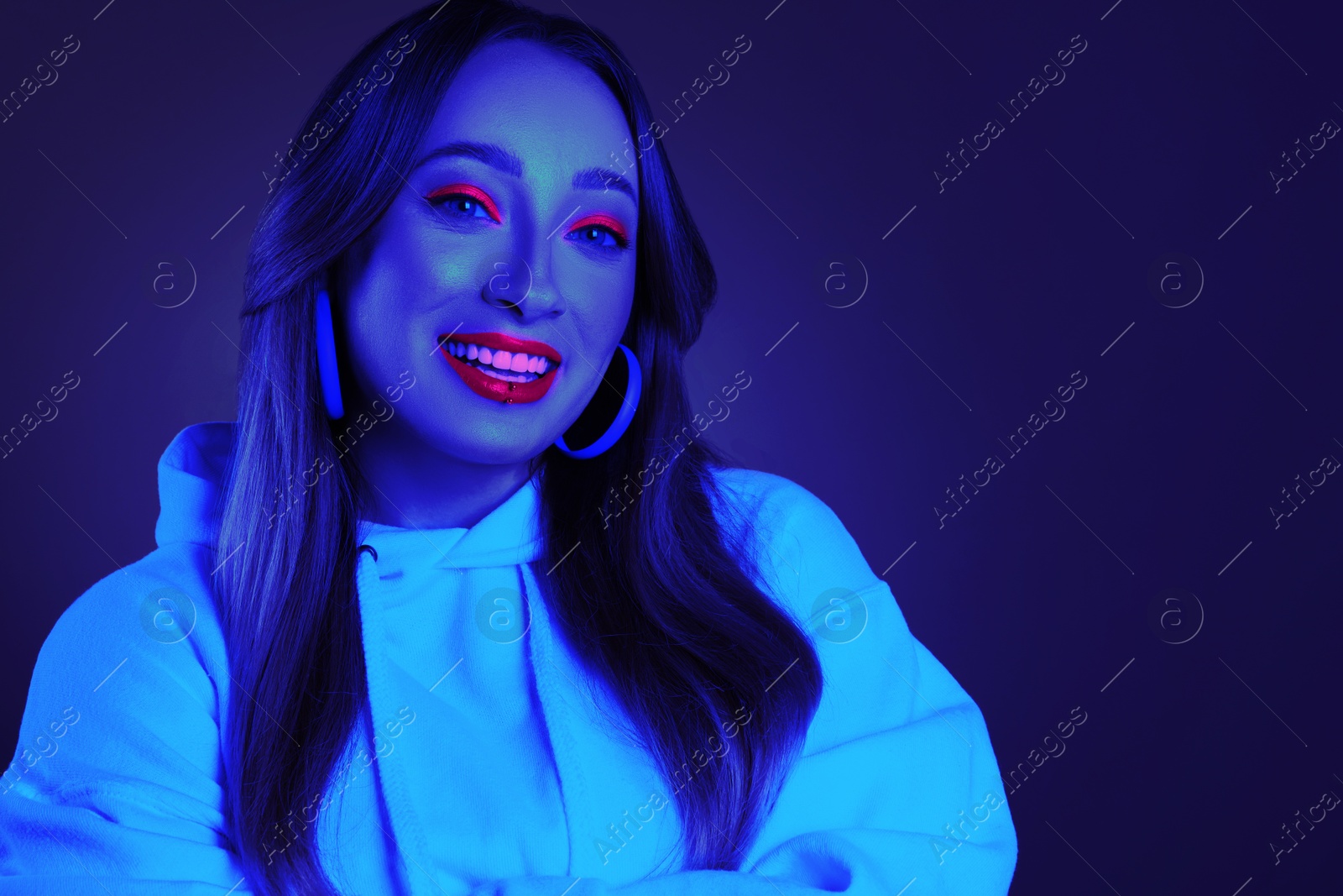 Image of Happy young woman with lip piercing in neon light, space for text