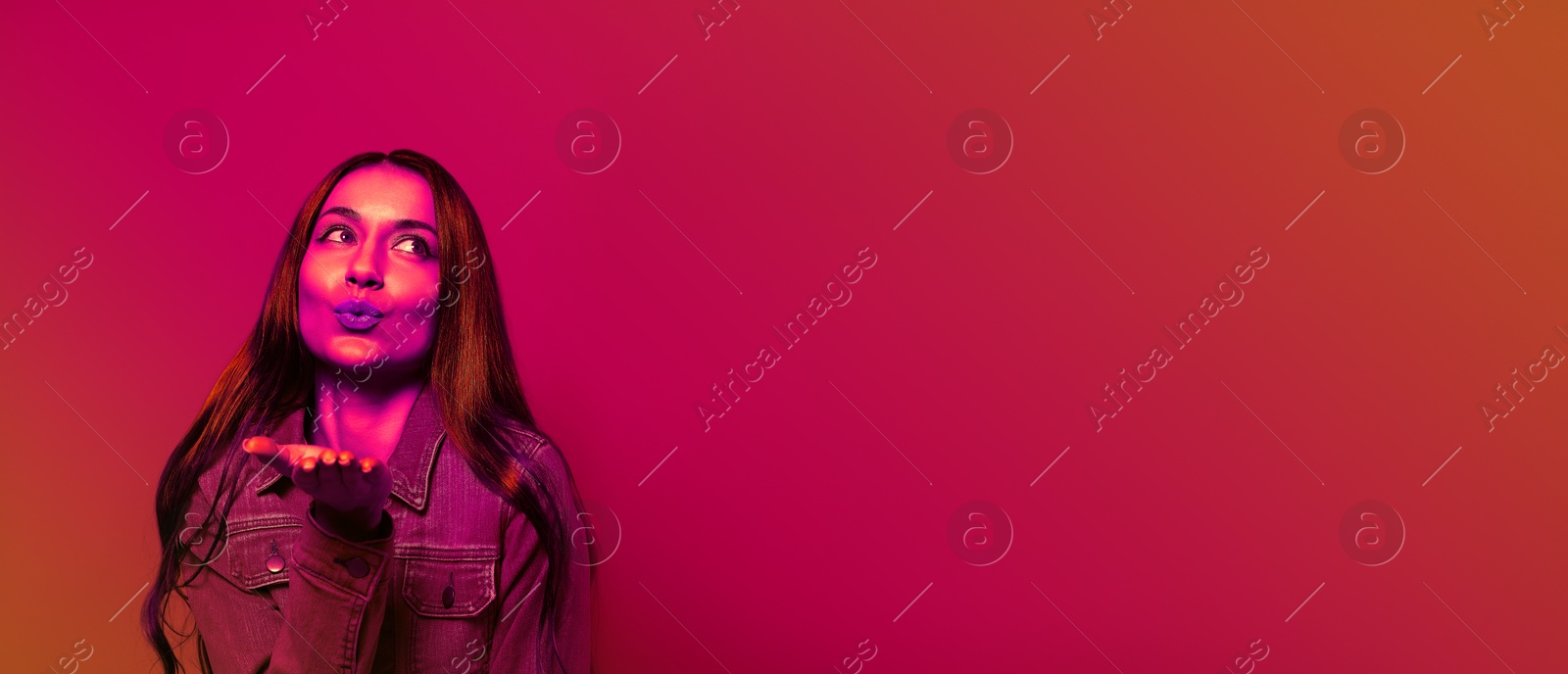 Image of Beautiful young woman blowing kiss in neon light, space for text. Banner design