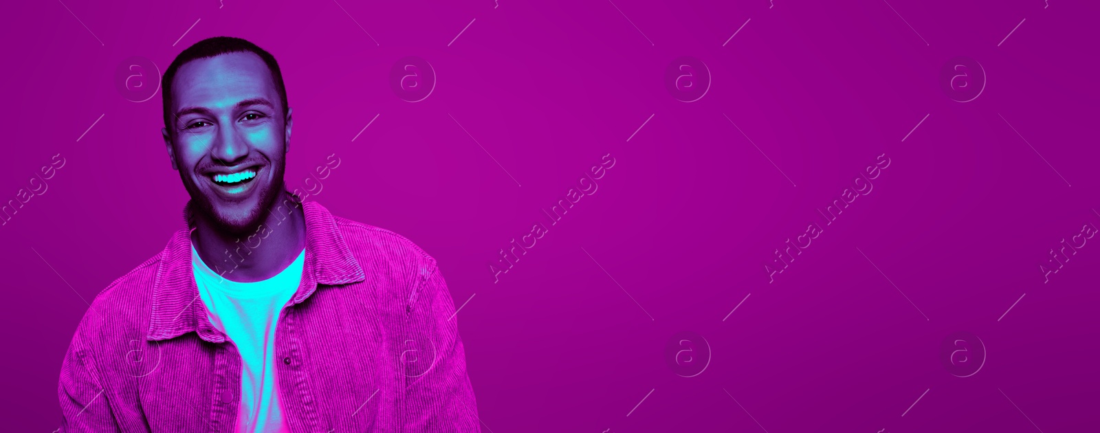 Image of Handsome man smiling in neon light, space for text. Banner design