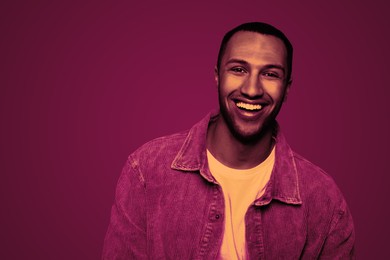 Image of Handsome man smiling in neon light, space for text