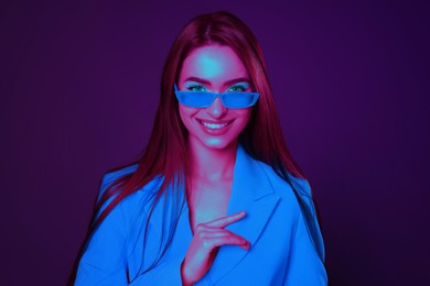 Image of Stylish woman with sunglasses in neon light