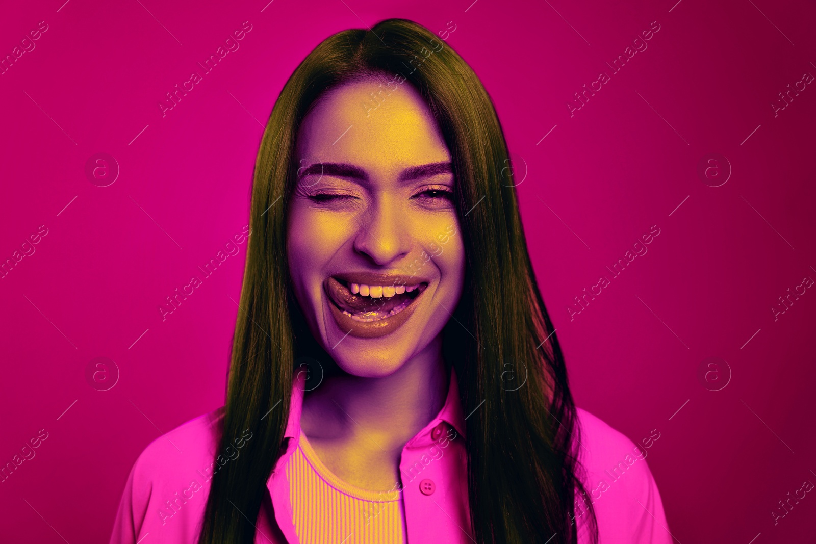 Image of Beautiful playful woman winking in neon light