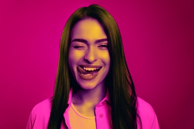 Image of Beautiful playful woman winking in neon light