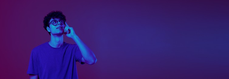 Image of Thoughtful young man in neon light, space for text. Banner design