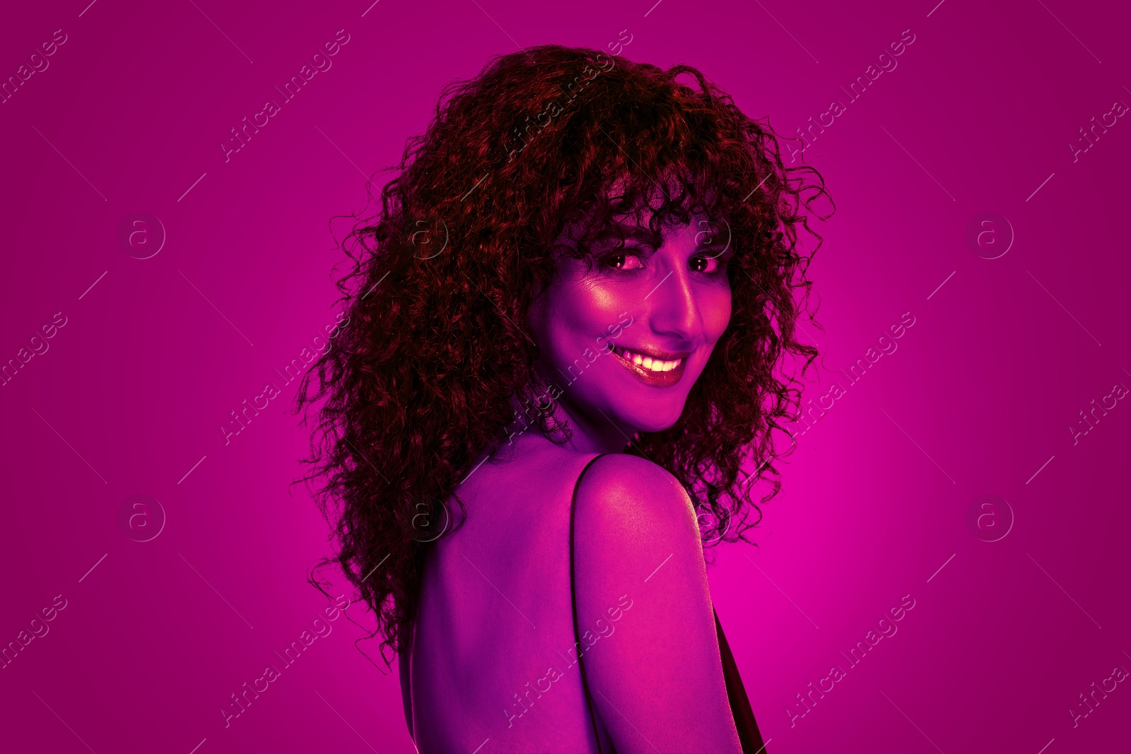 Image of Beautiful young woman with curly hair in neon light