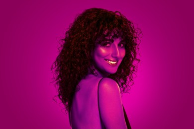 Image of Beautiful young woman with curly hair in neon light