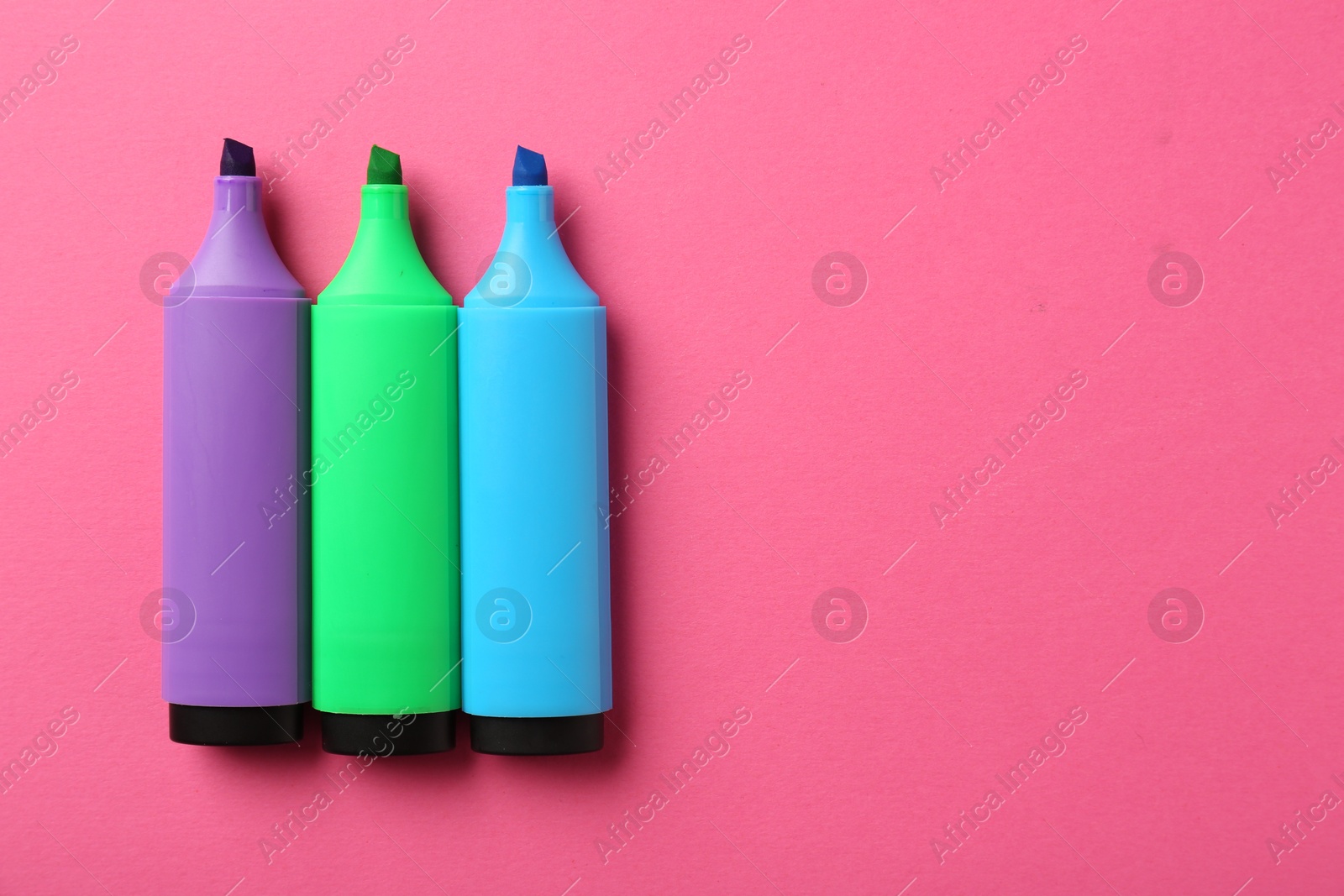 Photo of Bright highlighters on pink background, flat lay. Space for text