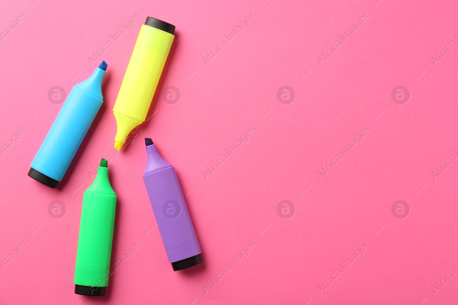 Photo of Bright highlighters on pink background, flat lay. Space for text