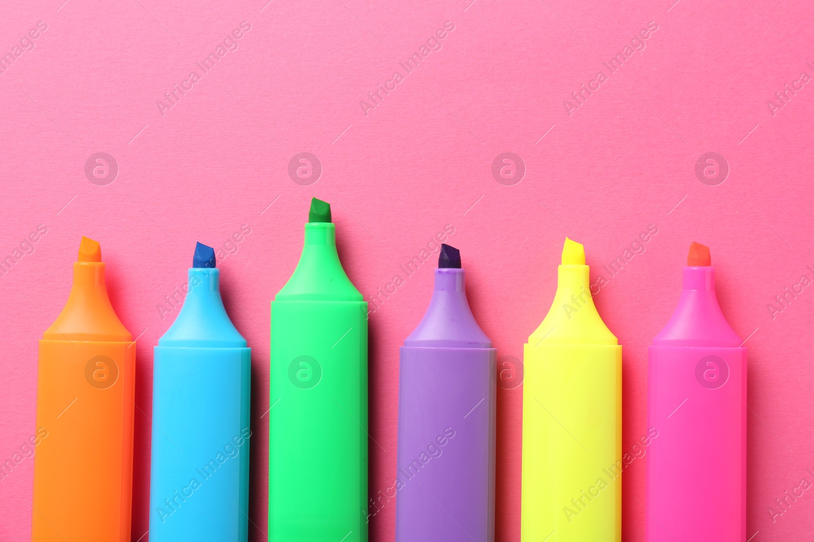 Photo of Bright highlighters on pink background, flat lay