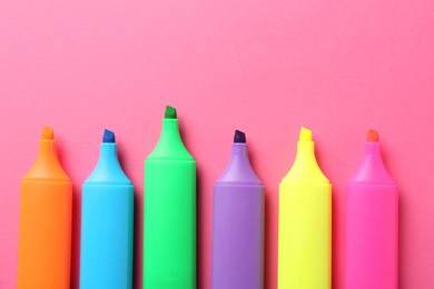 Photo of Bright highlighters on pink background, flat lay