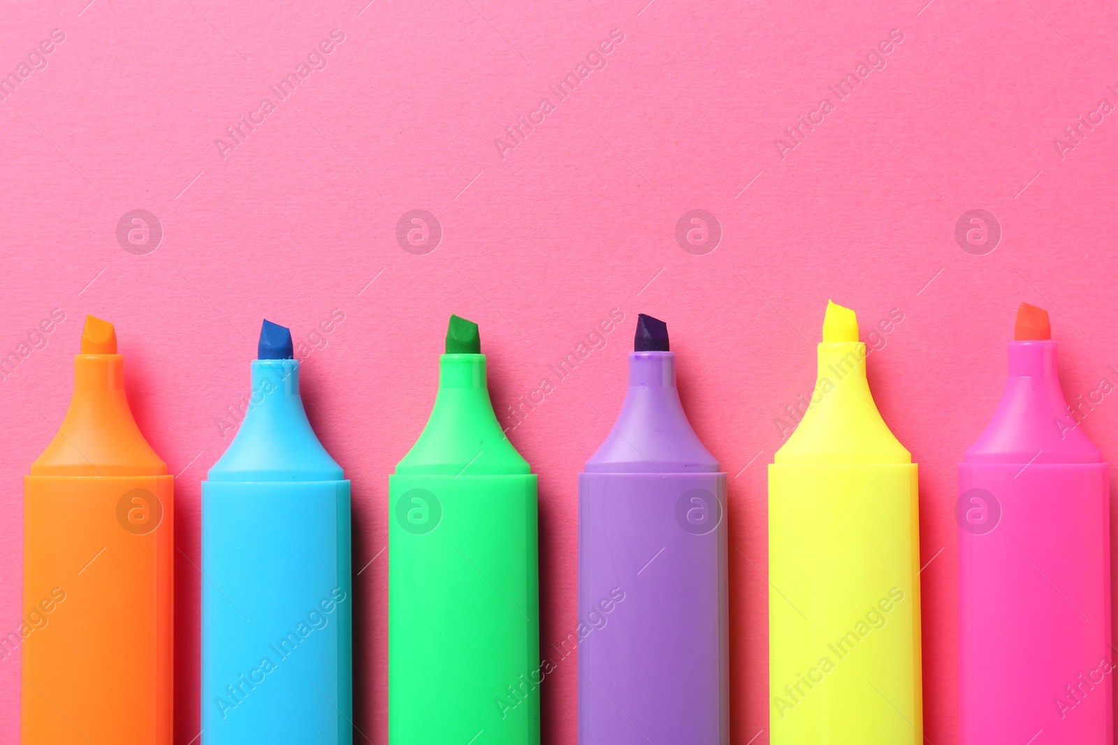 Photo of Bright highlighters on pink background, flat lay