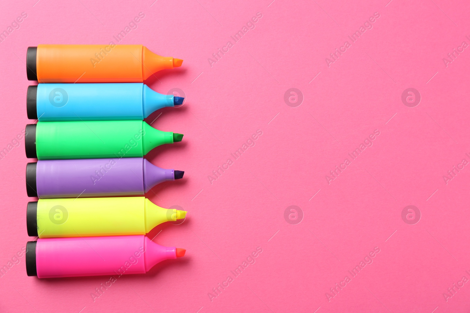 Photo of Bright highlighters on pink background, above view. Space for text