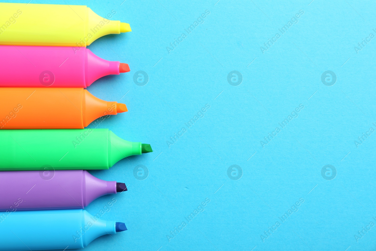 Photo of Bright highlighters on light blue background, above view. Space for text