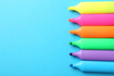 Photo of Bright highlighters on light blue background, above view. Space for text