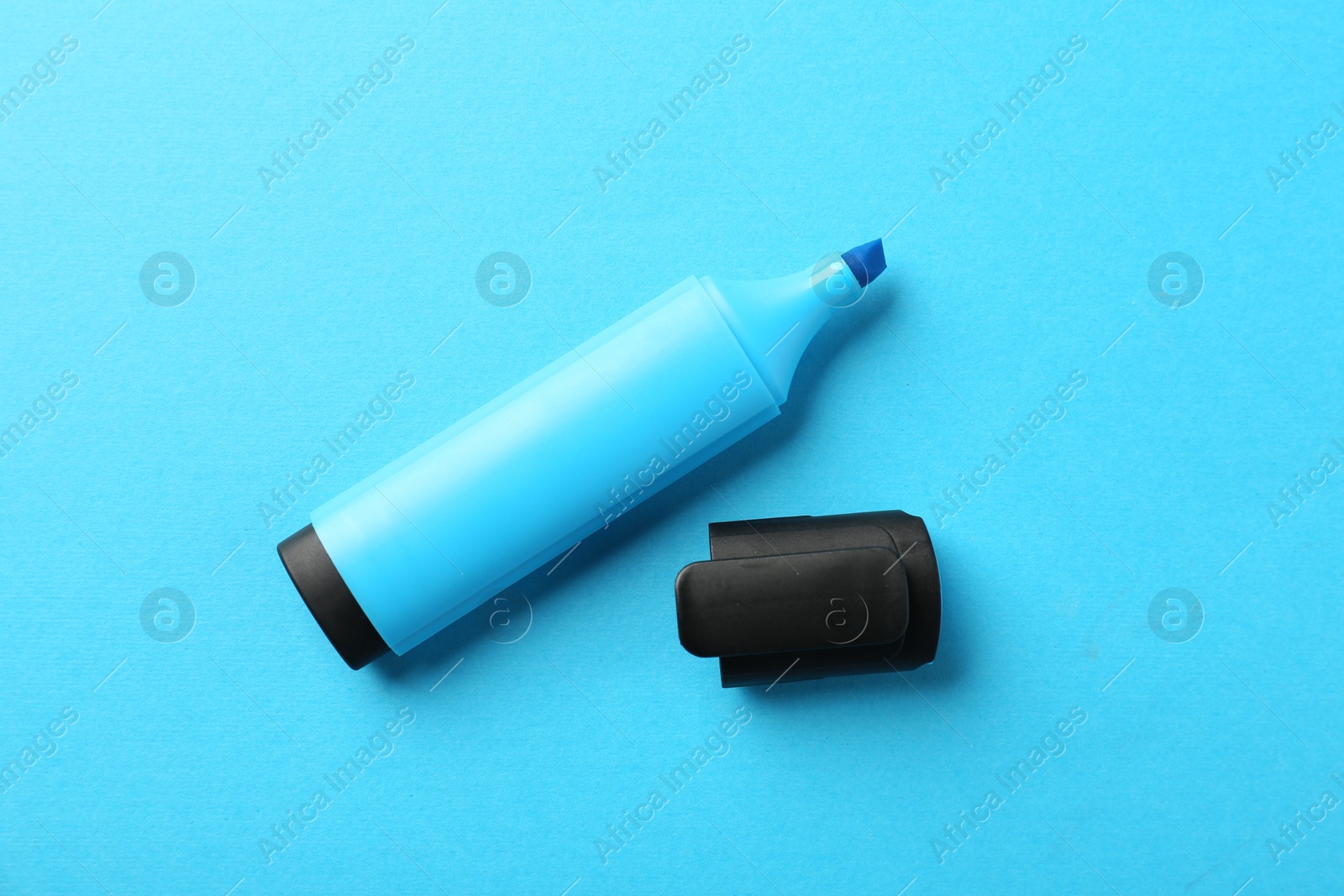 Photo of Bright highlighter and cap on light blue background, flat lay