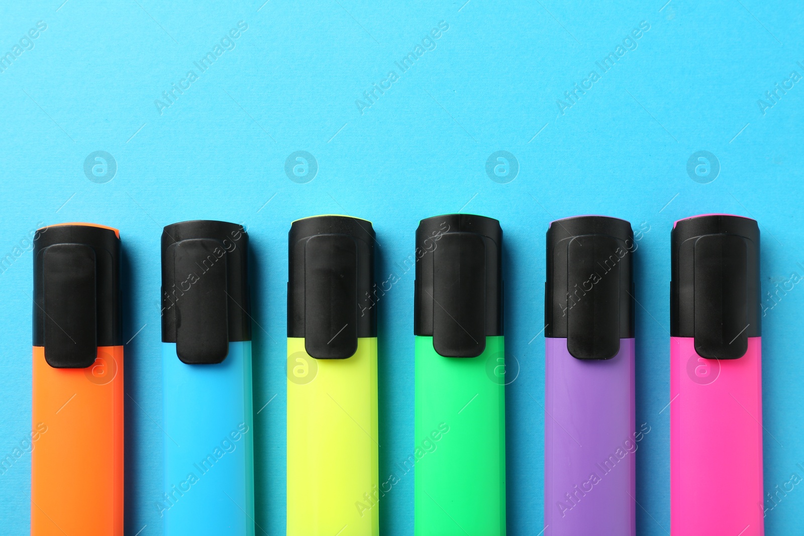 Photo of Bright highlighters on light blue background, flat lay