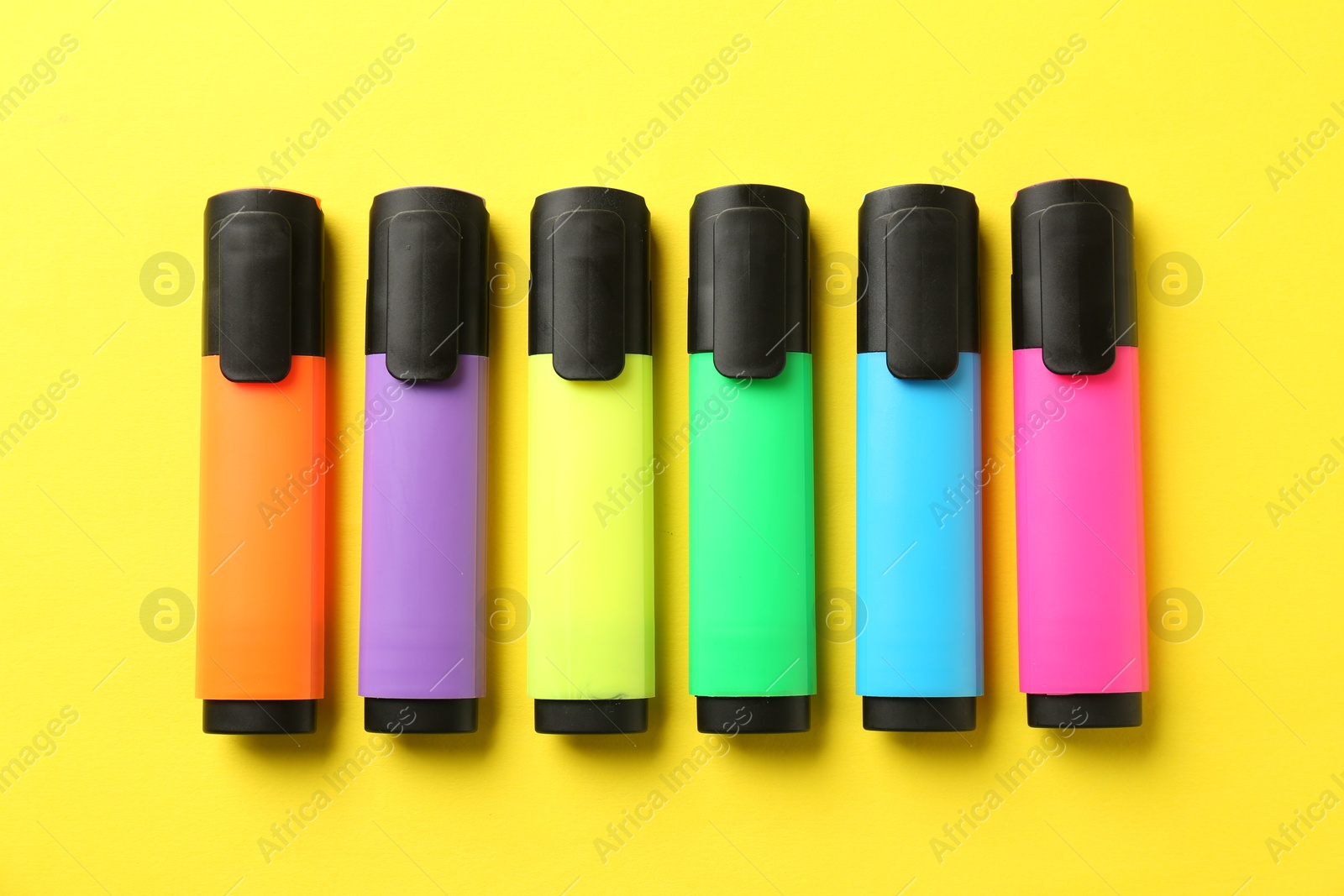 Photo of Bright highlighters on yellow background, flat lay