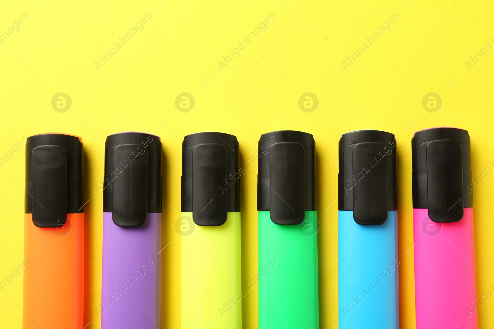 Photo of Bright highlighters on yellow background, flat lay