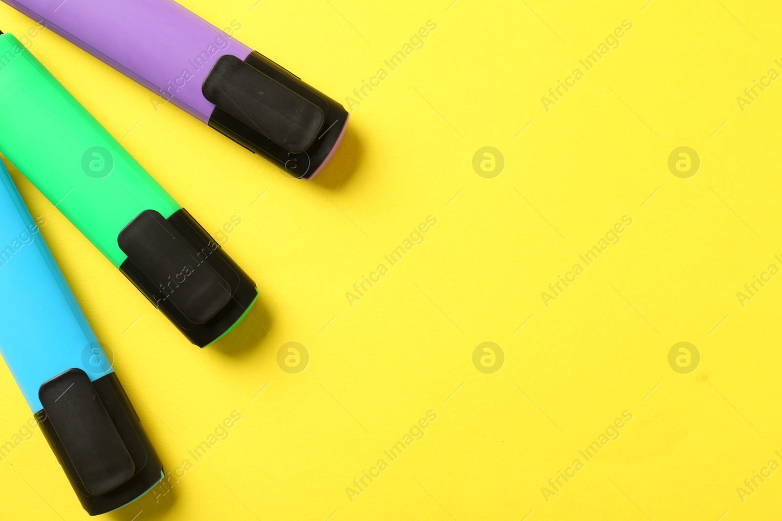 Photo of Bright highlighters on yellow background, flat lay. Space for text