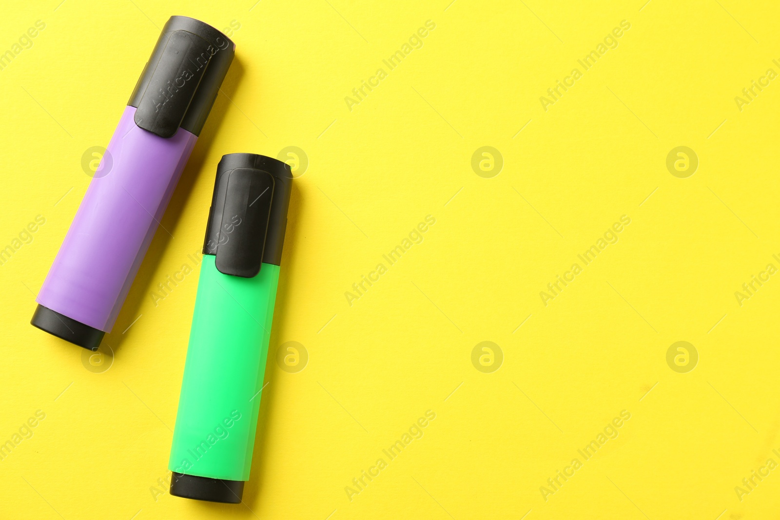 Photo of Bright highlighters on yellow background, flat lay. Space for text