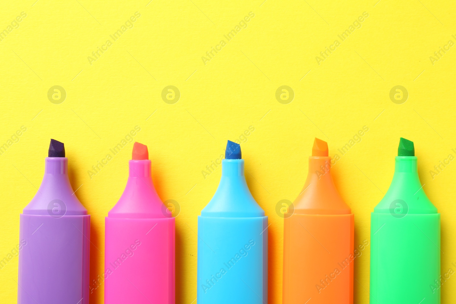 Photo of Bright highlighters on yellow background, flat lay. Space for text