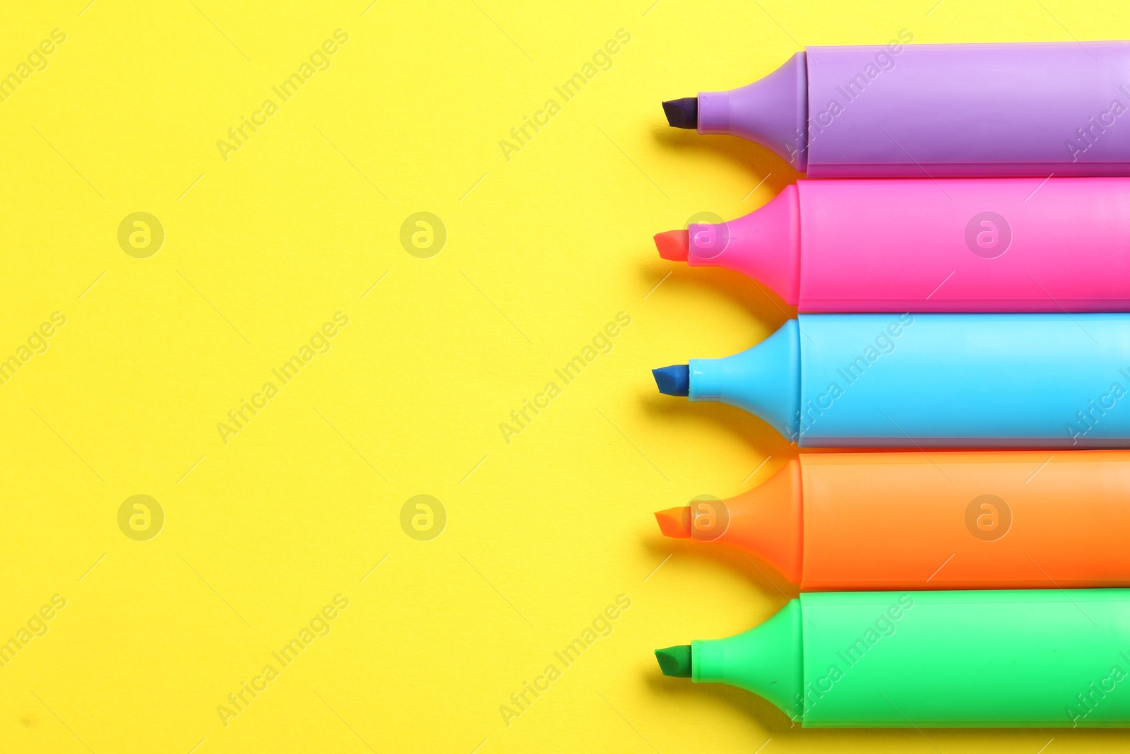 Photo of Bright highlighters on yellow background, above view. Space for text