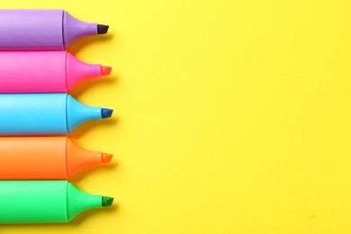 Photo of Bright highlighters on yellow background, above view. Space for text