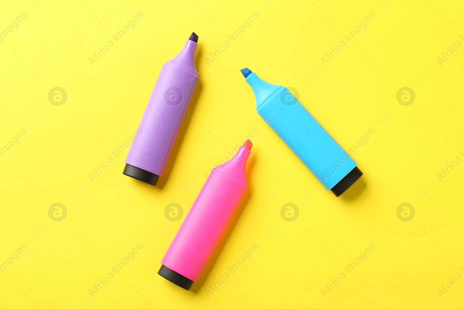 Photo of Bright highlighters on yellow background, flat lay