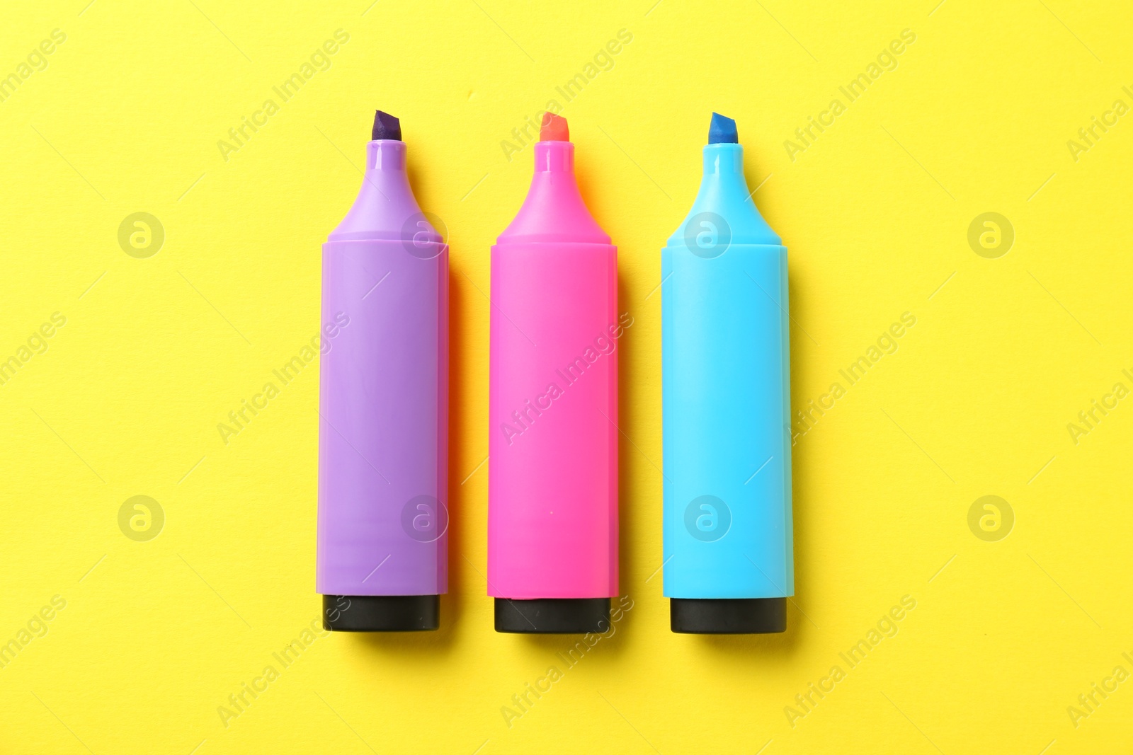 Photo of Bright highlighters on yellow background, flat lay