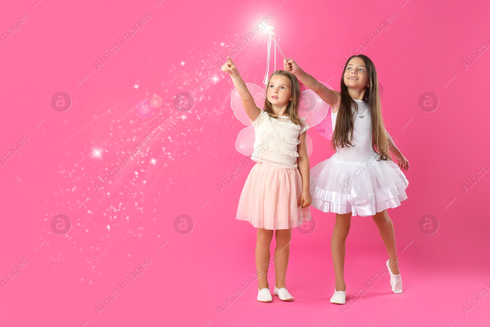 Image of Cute girls with fairy wings on pink background. Magic lights around