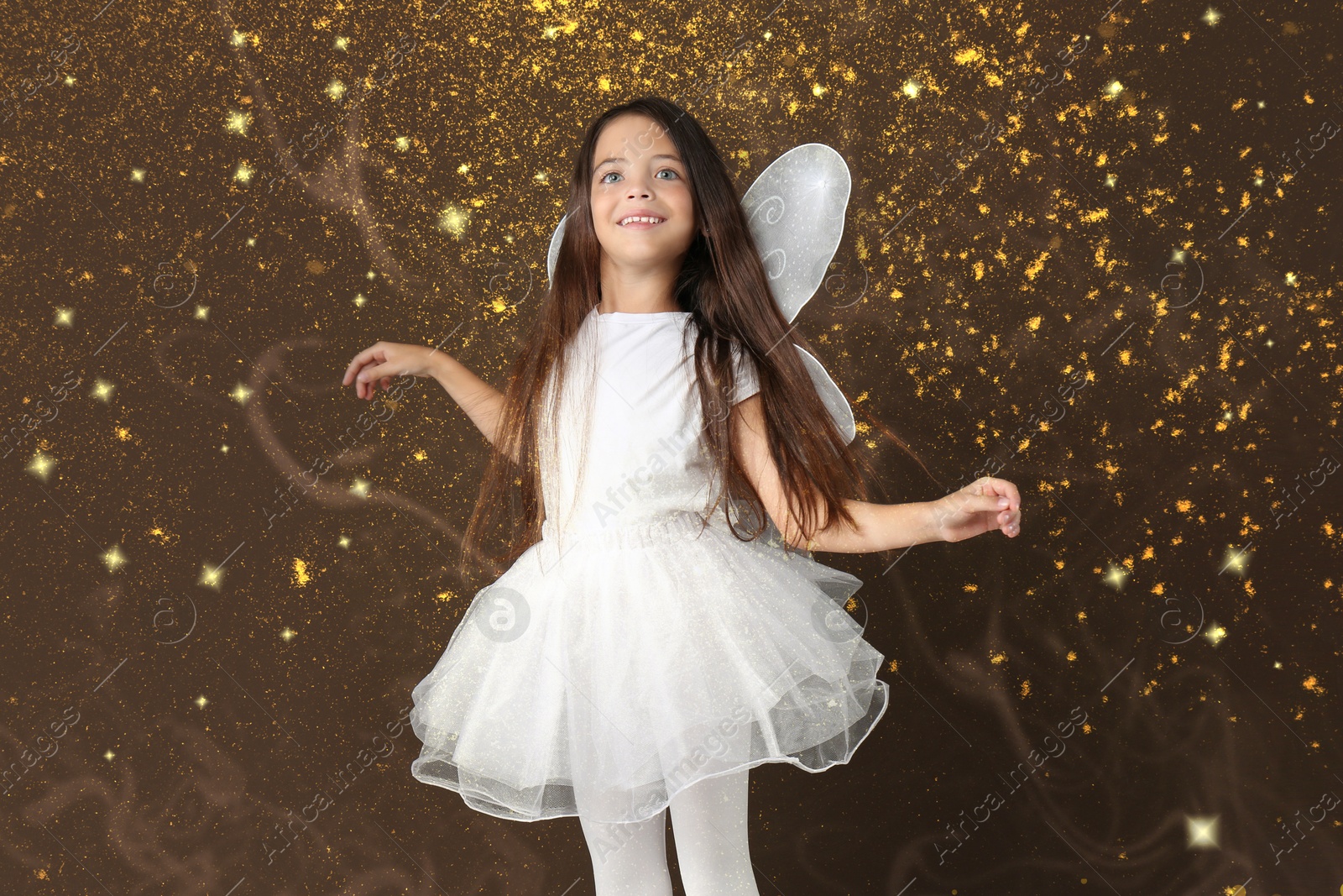 Image of Cute girl with fairy wings on brown background. Magic lights around