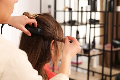 Photo of Stylist working with client in salon, making hairstyle