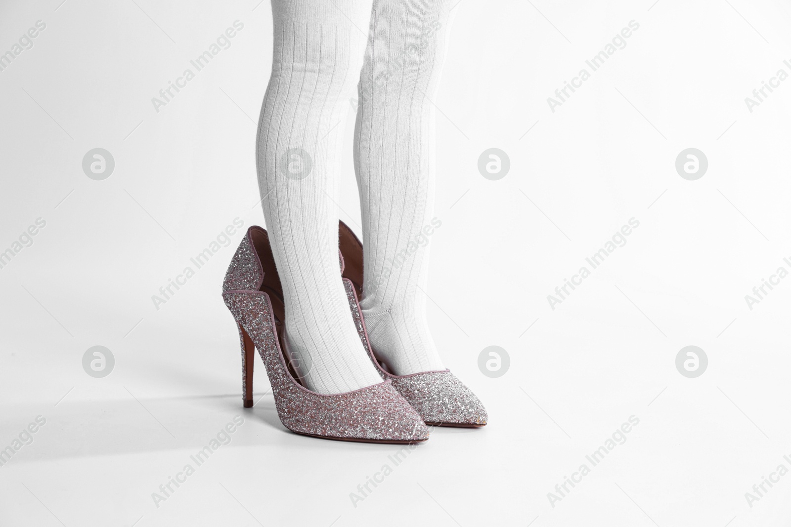 Photo of Child wearing tights and heels on white background, closeup