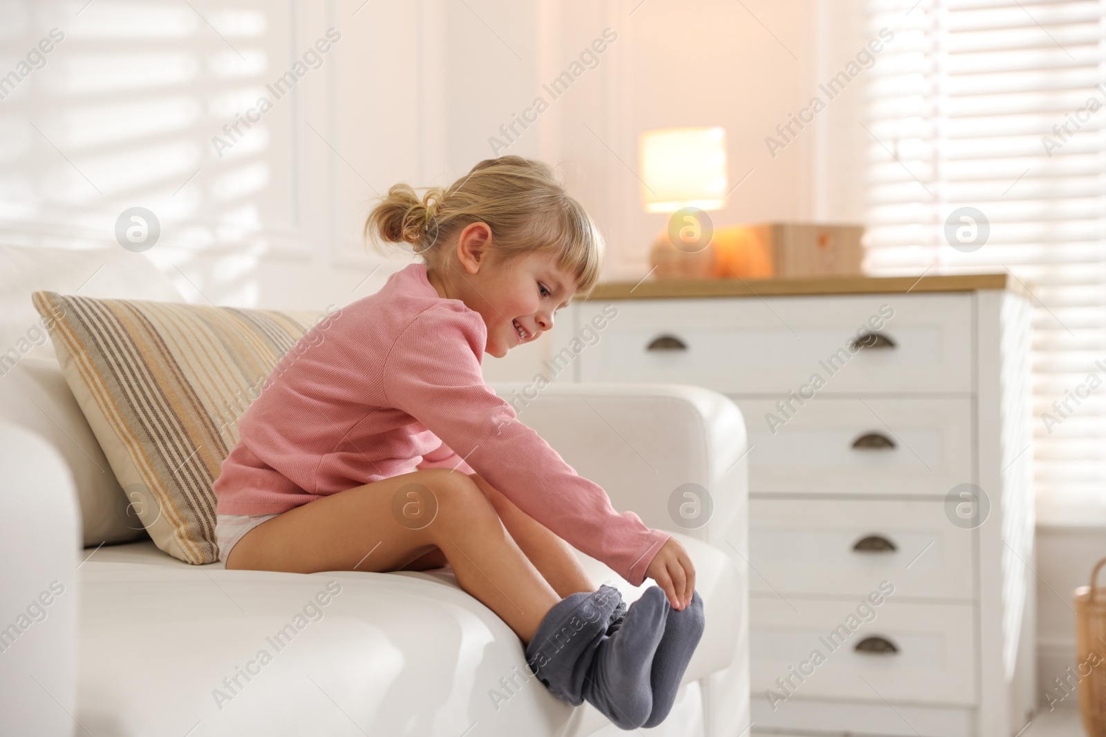 Photo of Little girl putting on soft tights at home. Space for text