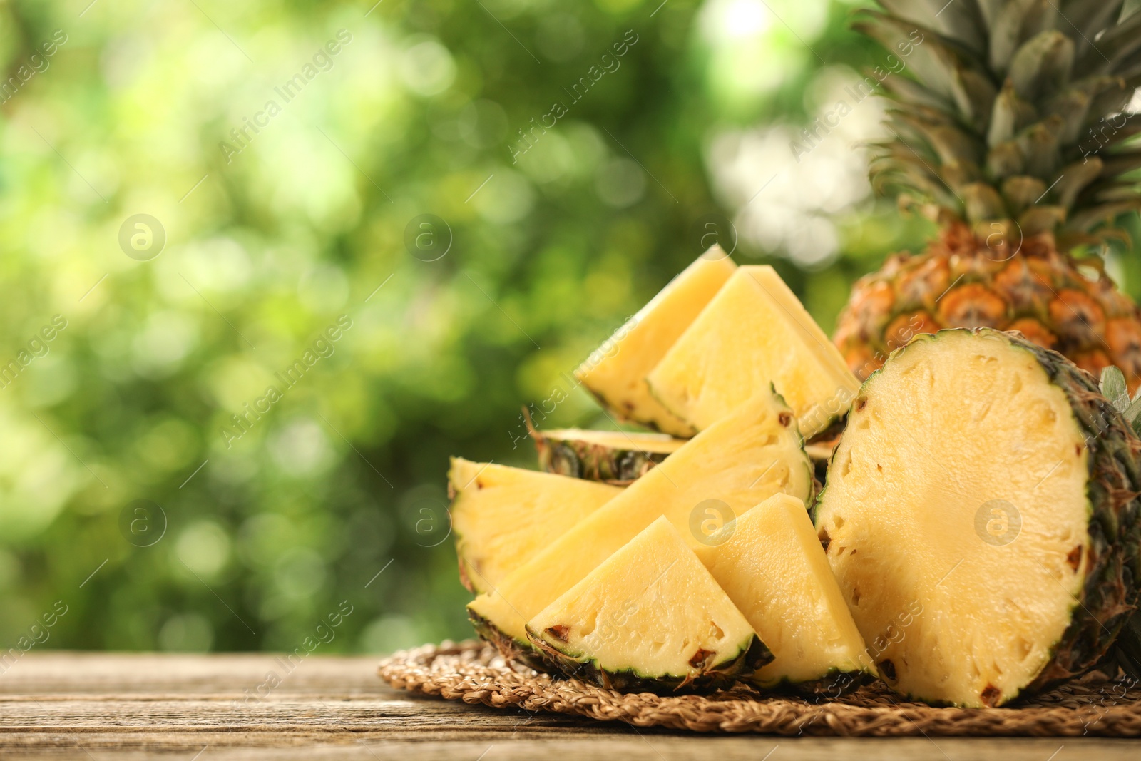 Photo of Fresh ripe pineapples on wooden table against blurred background, closeup. Space for text