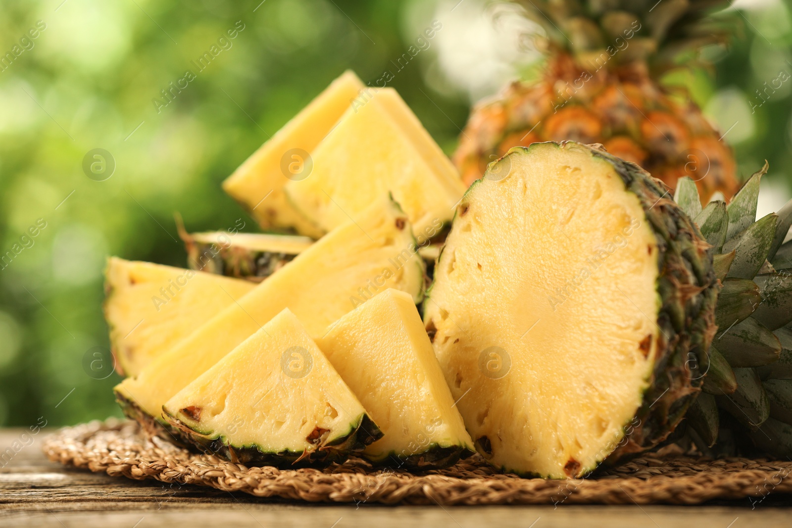 Photo of Fresh ripe pineapples on wooden table against blurred background, closeup