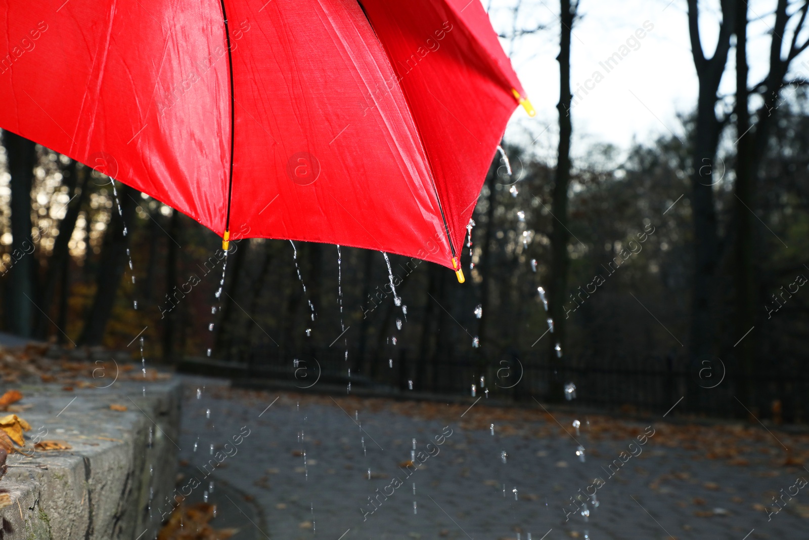 Photo of Open red umbrella under pouring rain outdoors, closeup. Space for text