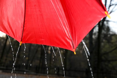 Photo of Open red umbrella under pouring rain outdoors, closeup