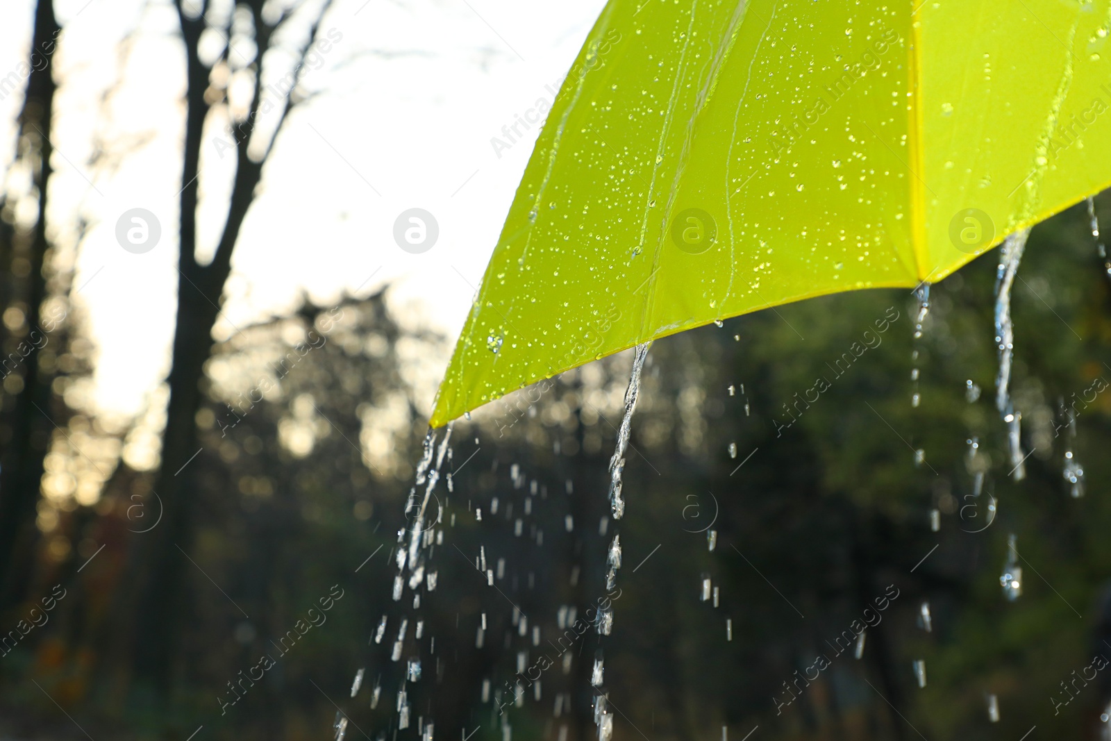 Photo of Open yellow umbrella under pouring rain outdoors, closeup