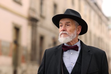 Photo of Portrait of elegant senior man in hat outdoors. Space for text