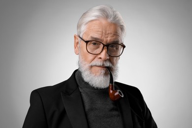 Photo of Senior man with tobacco pipe on light grey background