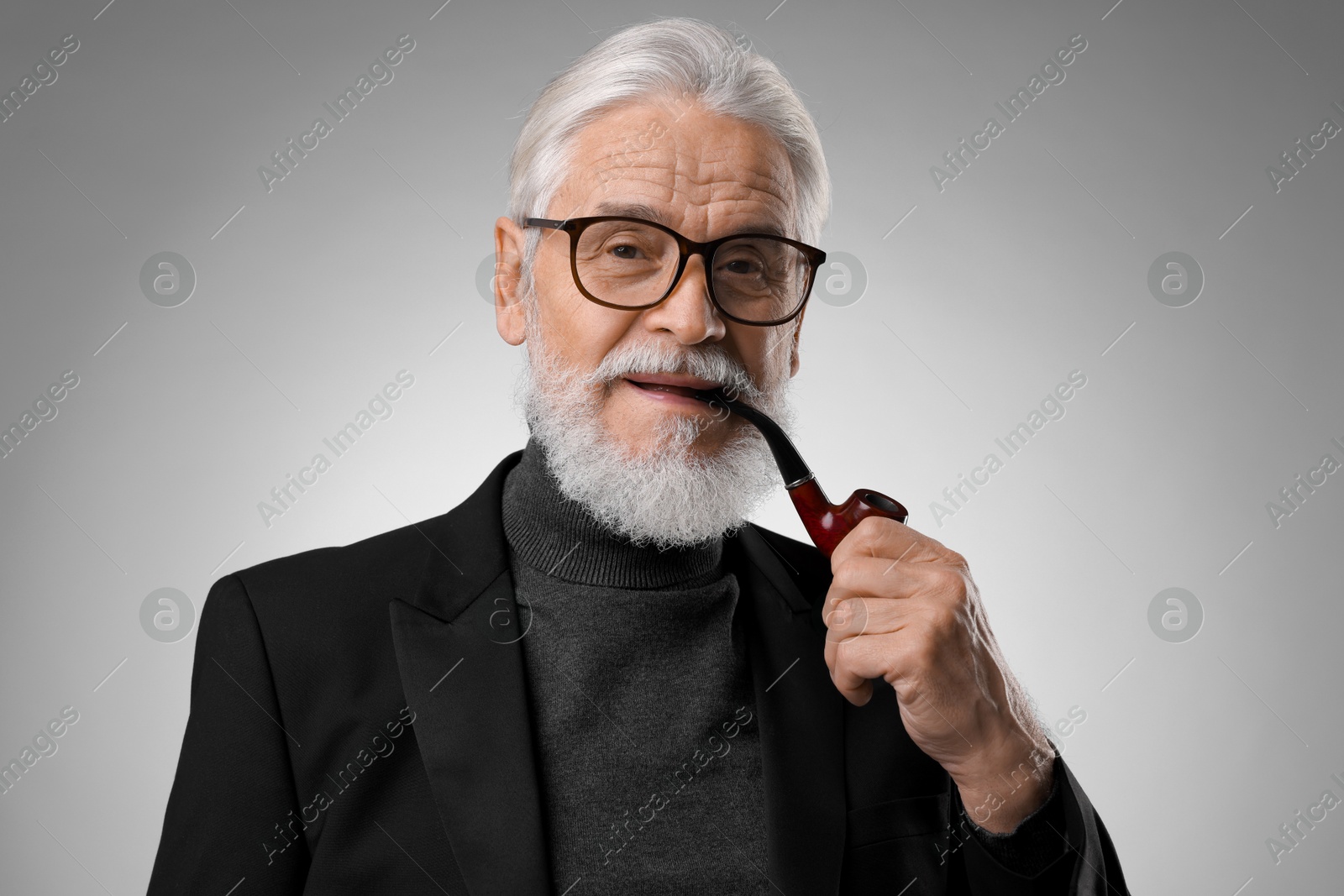 Photo of Senior man with tobacco pipe on light grey background