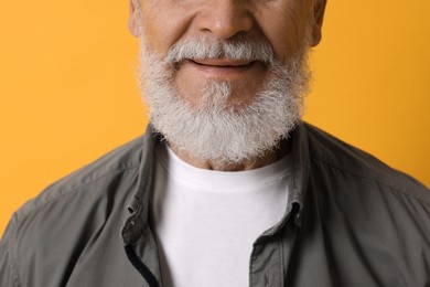 Photo of Senior man with gray beard on orange background, closeup