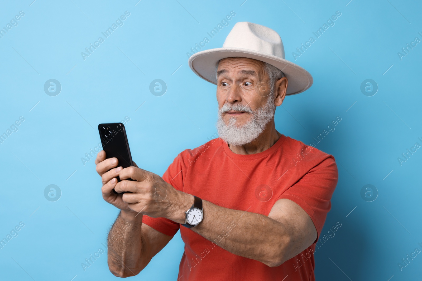 Photo of Emotional senior man with smartphone on light blue background