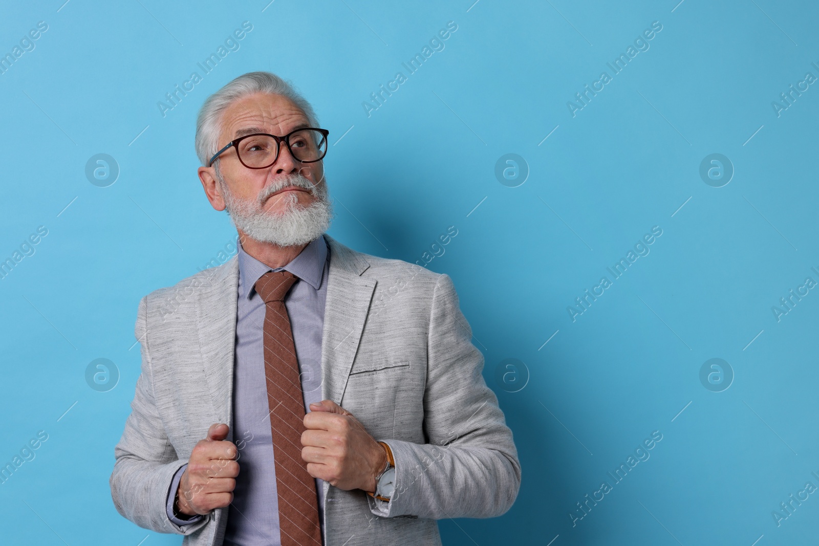 Photo of Portrait of senior man with gray beard on light blue background. Space for text