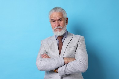 Photo of Portrait of serious senior man with silver beard on light blue background