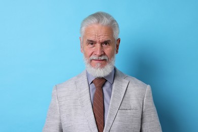 Photo of Portrait of serious senior man with silver beard on light blue background