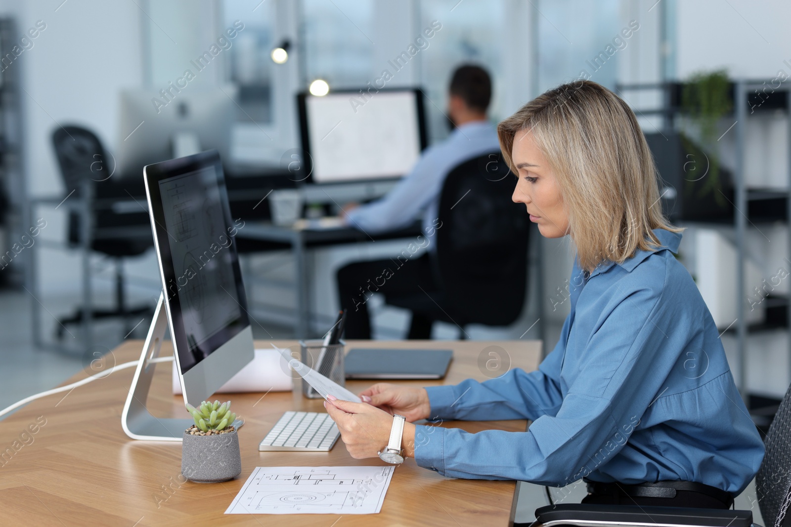 Photo of Technician making digital engineering drawing on computer at desk in office