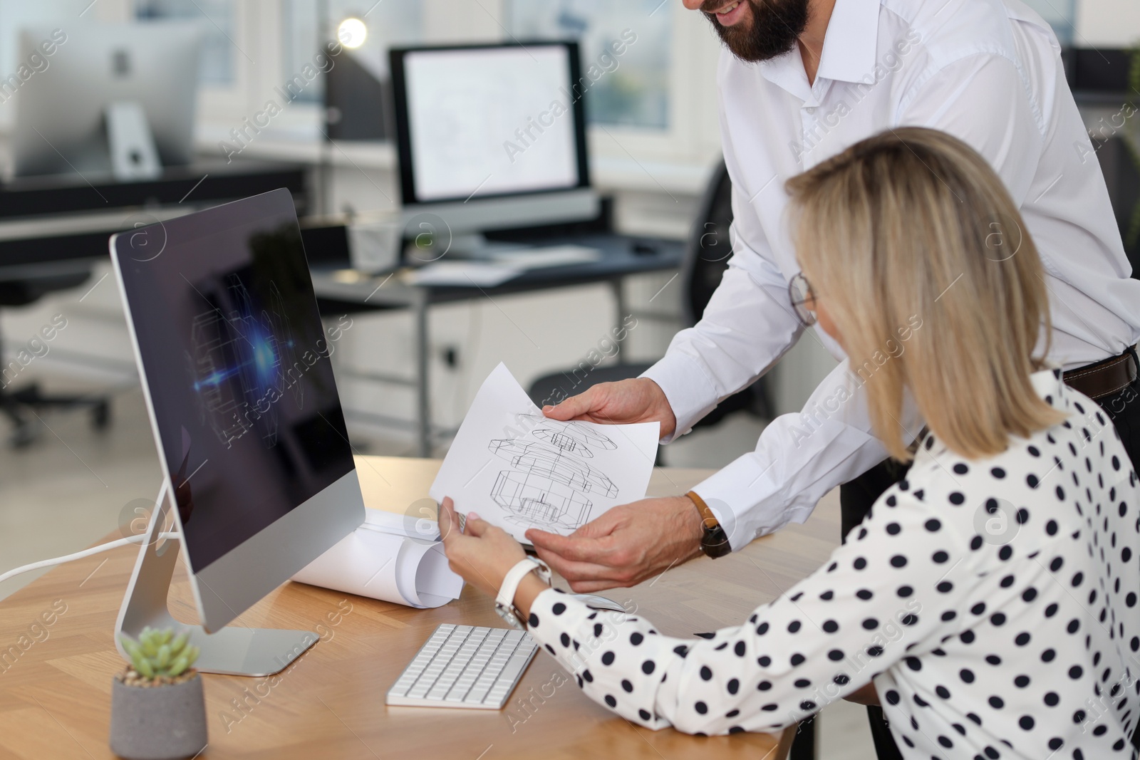 Photo of Technicians making digital engineering drawing on computer at desk in office