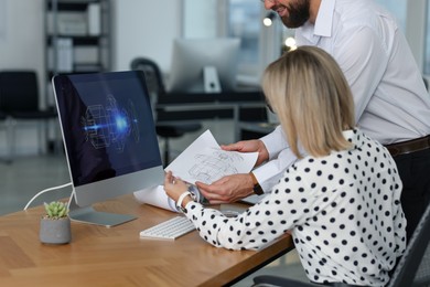 Photo of Technicians making digital engineering drawing on computer at desk in office